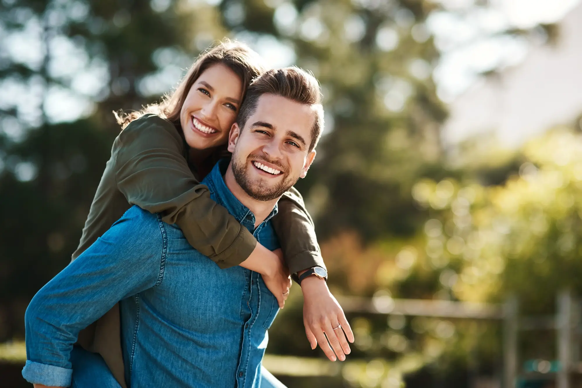 A couple laughing together outdoors surrounded by greenery