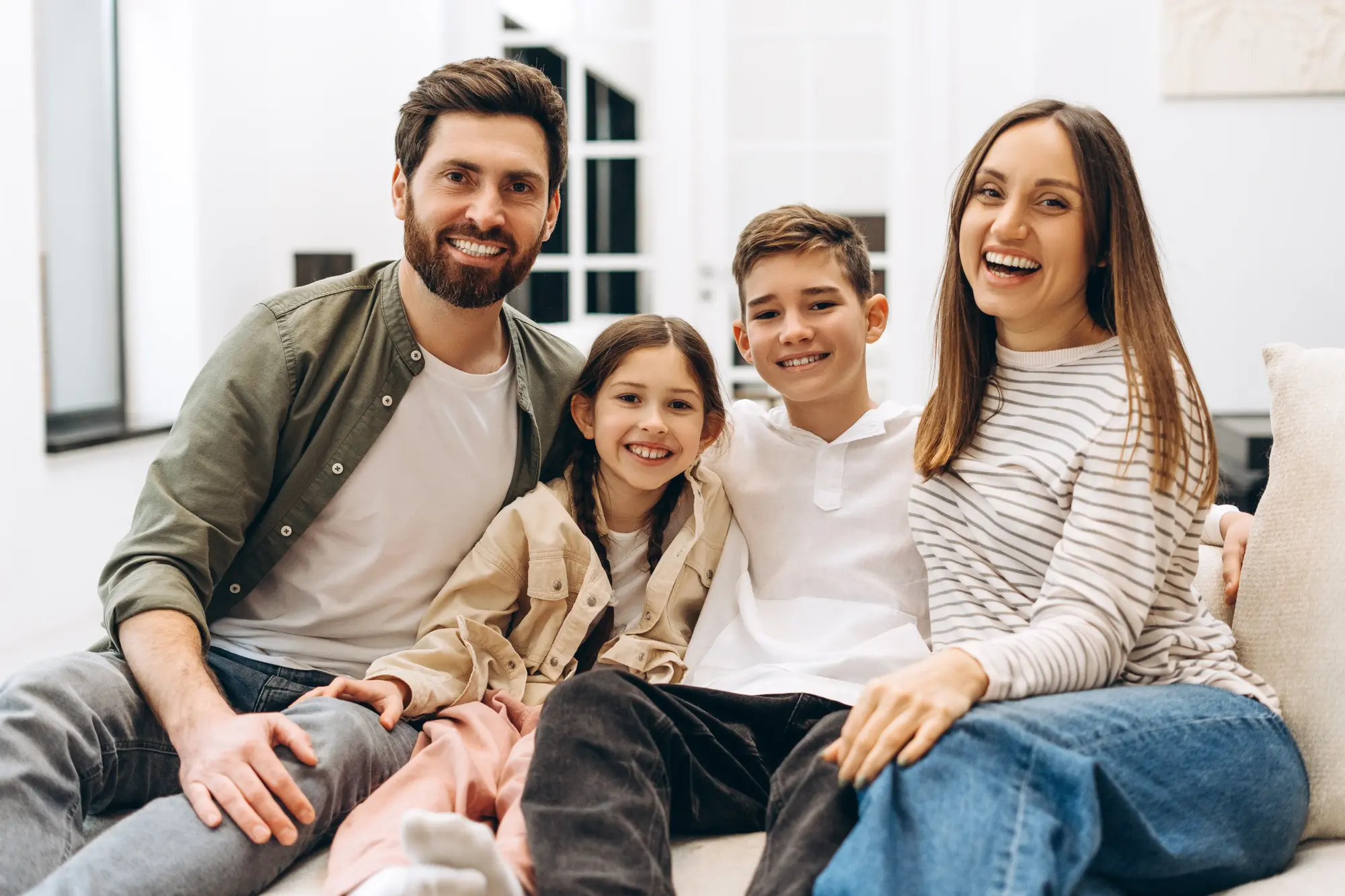 A family of four laughing together on a couch at home