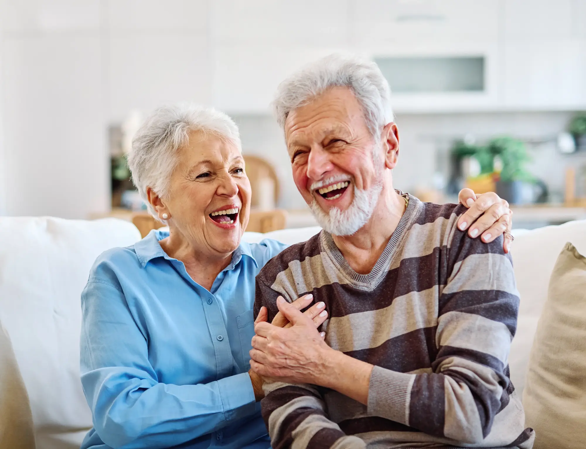 An older couple laughing together on a couch